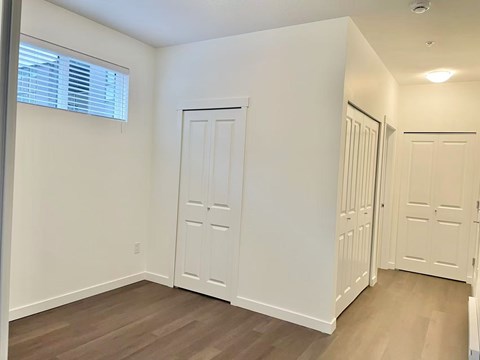 A room with a white door and wooden flooring.