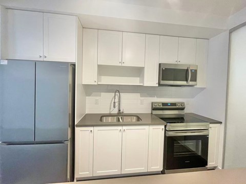A kitchen with white cabinets and a stainless steel refrigerator.