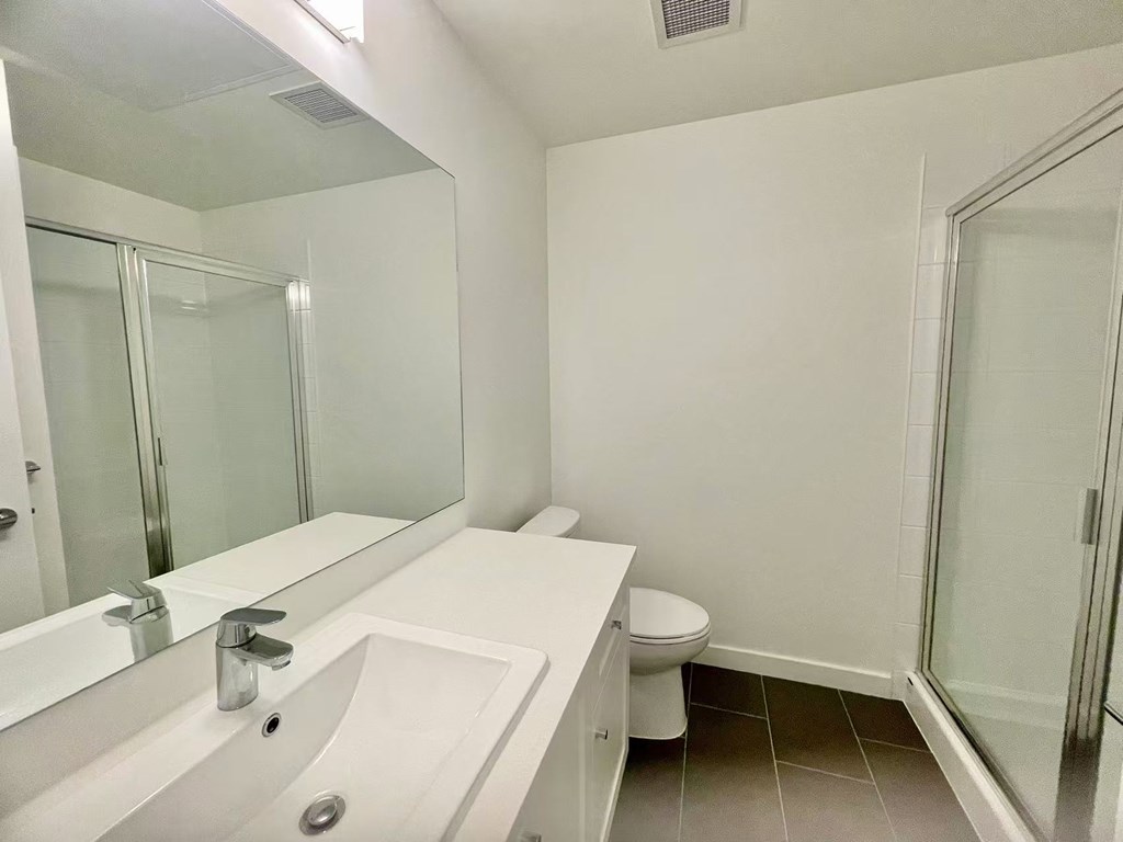 A white bathroom with a toilet, sink, and mirror.