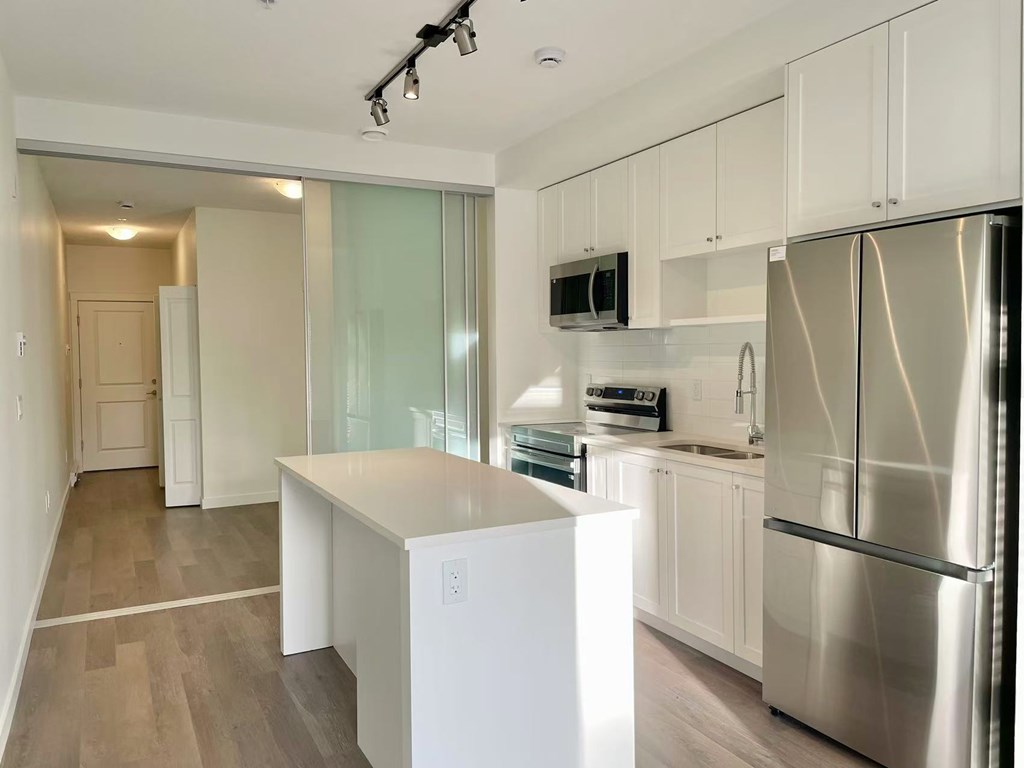 A modern kitchen with a refrigerator, microwave, and oven.