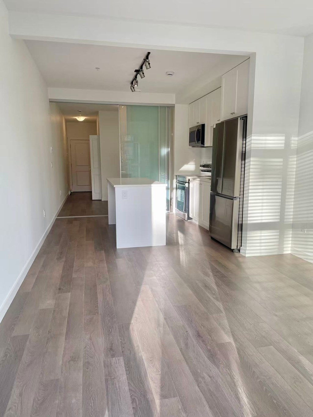 A kitchen with a refrigerator, microwave, and oven.