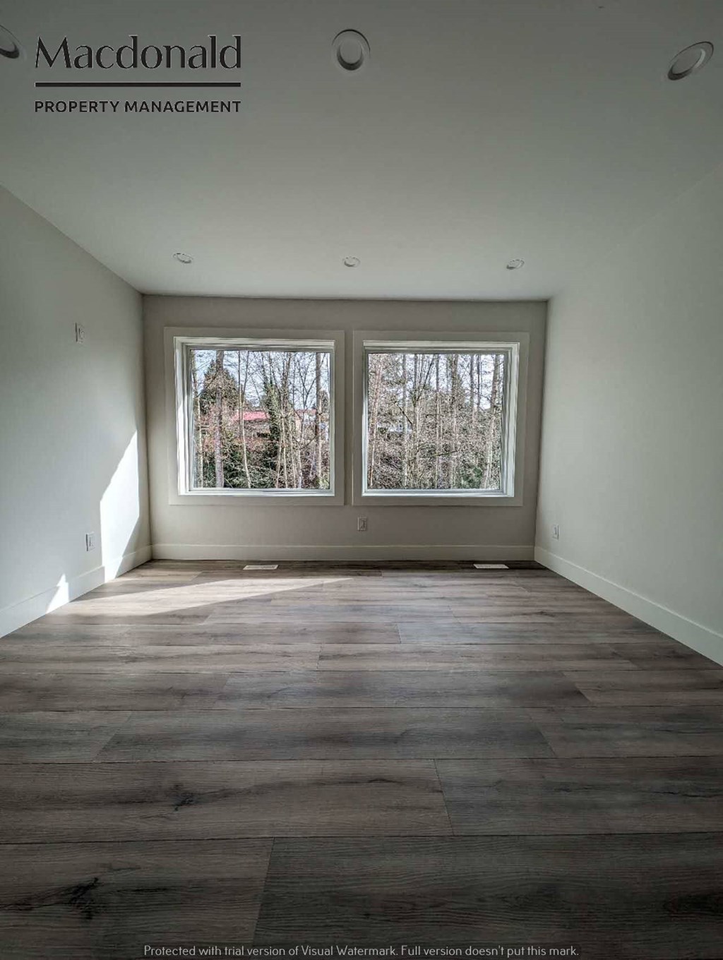 a empty living room with three windows and wood floors