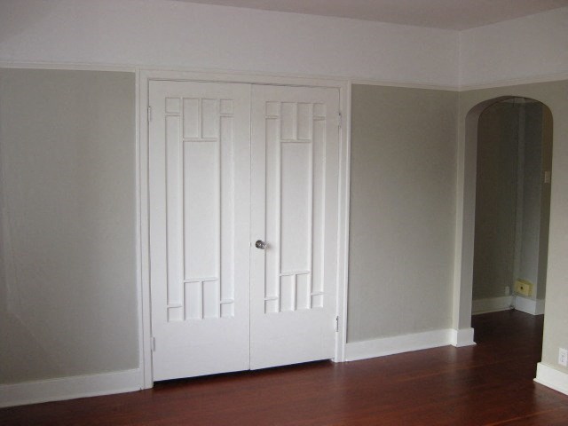 A white door with a silver handle is in a room with wooden floors.