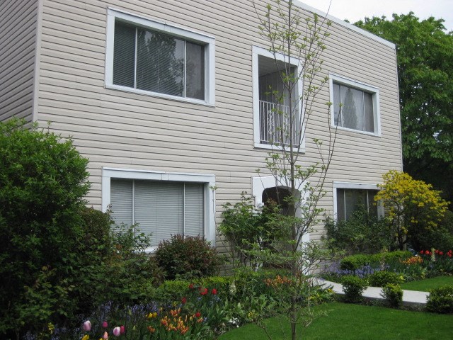 A beige house with a garden in front.