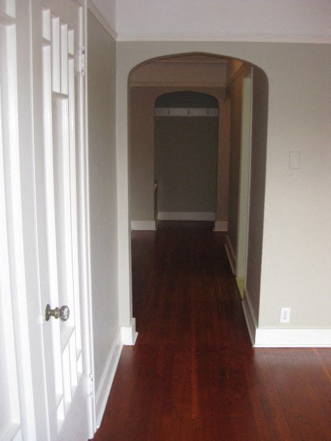 A hallway with a white door and a brown arch.
