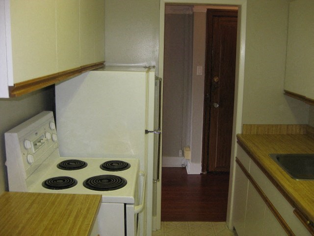 A white stove in a kitchen with a wooden counter top.