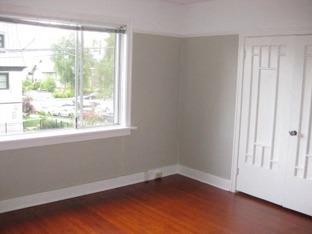 A room with a white door and a window overlooking a street.