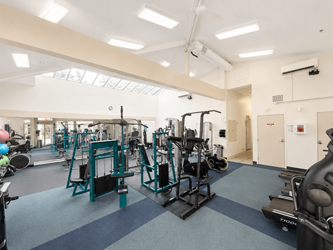 A gym with a variety of equipment including weights and cardio machines.