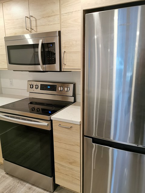 A stainless steel refrigerator stands next to a stove and microwave in a modern kitchen.