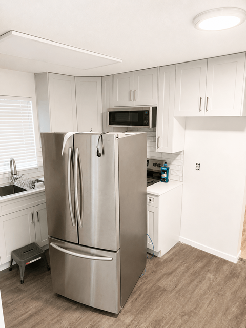 A kitchen with a stainless steel refrigerator and white cabinets.