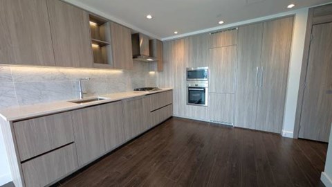 A modern kitchen with wooden cabinets and a marble backsplash.