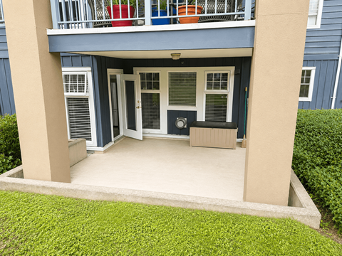 A small balcony with a white door and a window with blinds.