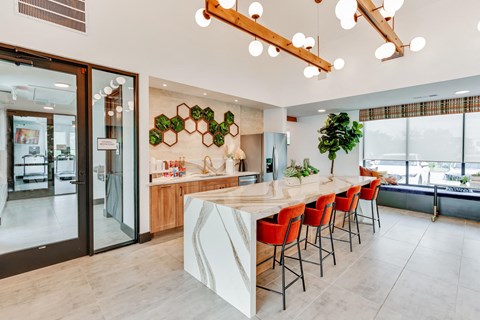 a kitchen with a marble counter top and a long bar with red chairs