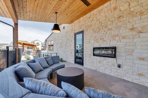 A modern living room with a curved sofa and a stone wall.