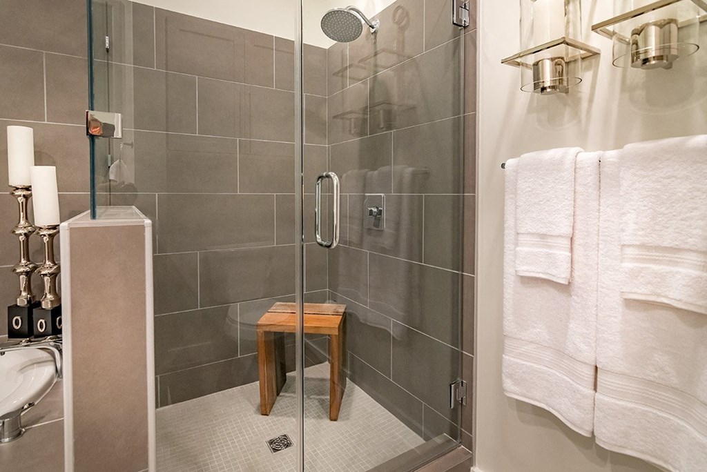 a bathroom with a shower and white towels and a wooden stool