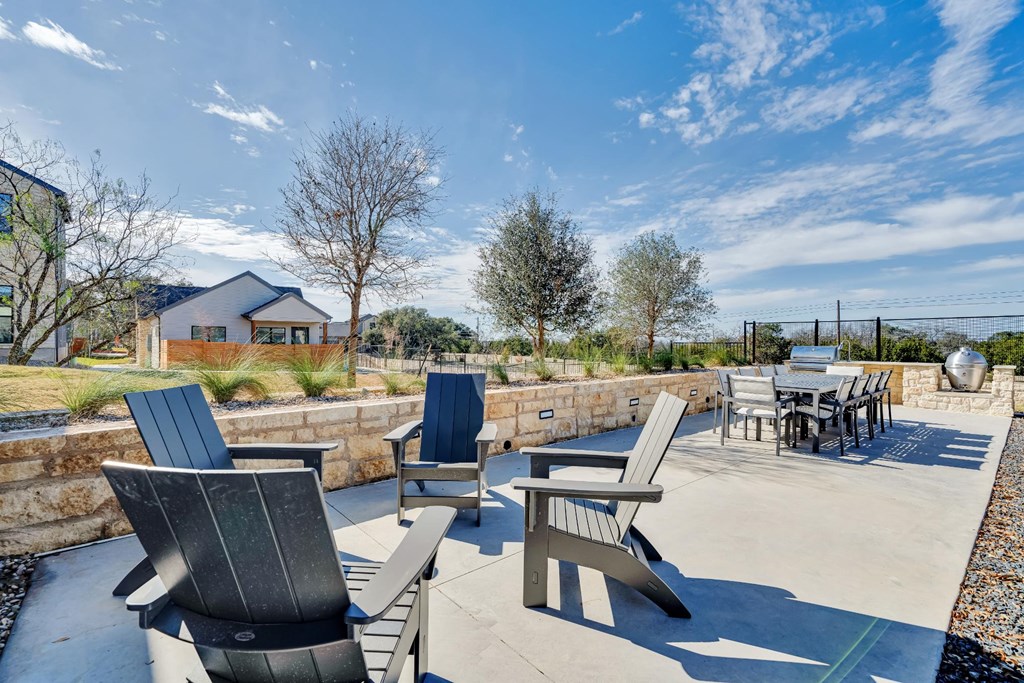 A patio with a table and chairs is surrounded by a stone wall.