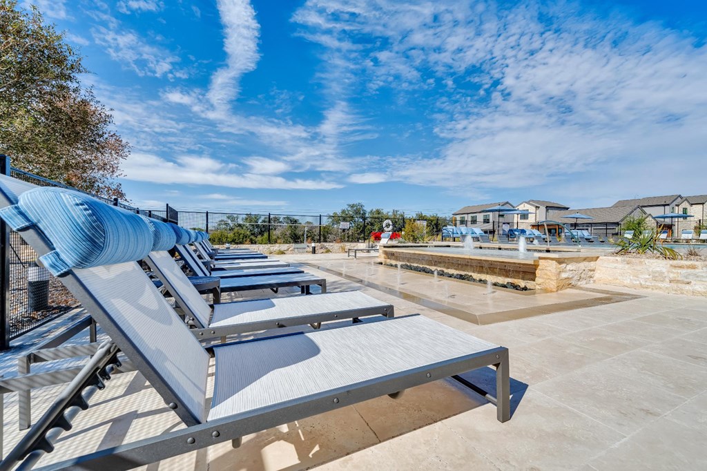 A row of sun loungers are on a concrete surface.