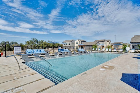 A large outdoor swimming pool surrounded by lounge chairs.