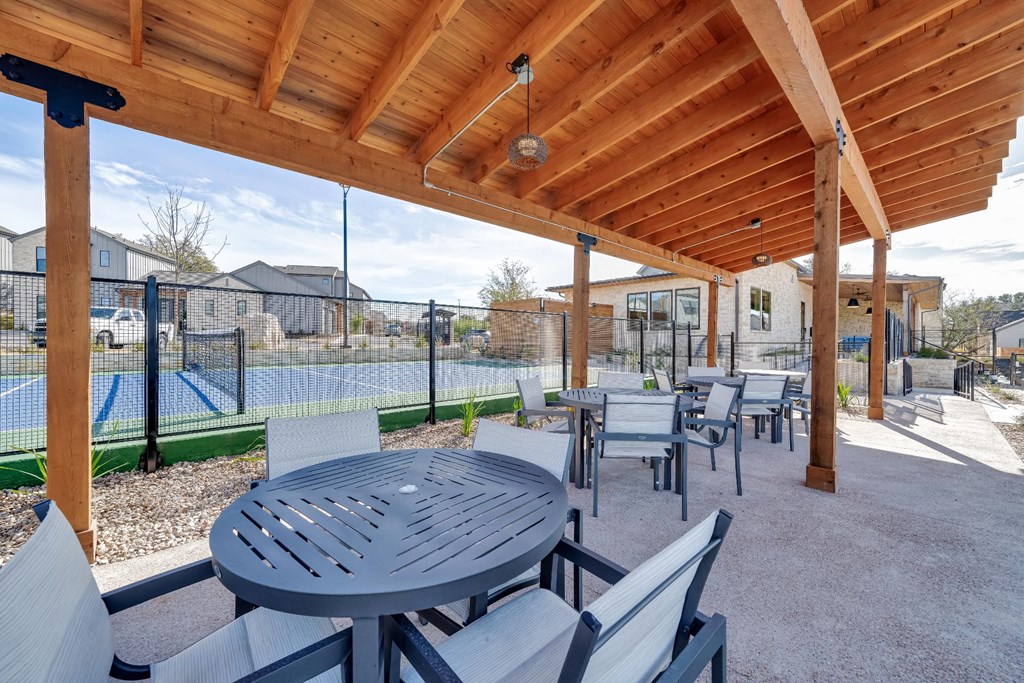 A wooden pergola over a table and chairs.