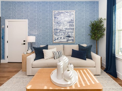 A living room with a white couch and a blue wallpaper.