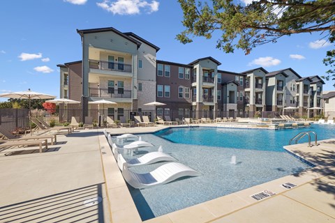 A large swimming pool in front of apartment buildings.