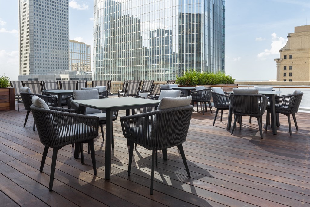 a rooftop patio with tables and chairs and tall buildings