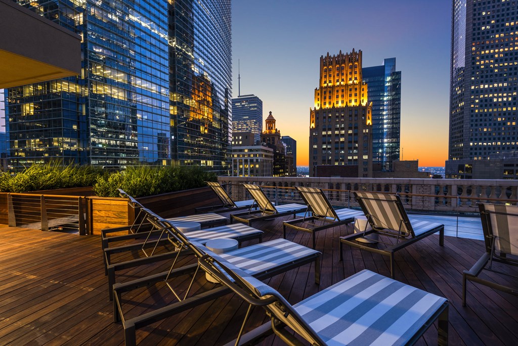 a rooftop terrace with chairs and tables and skyscrapers