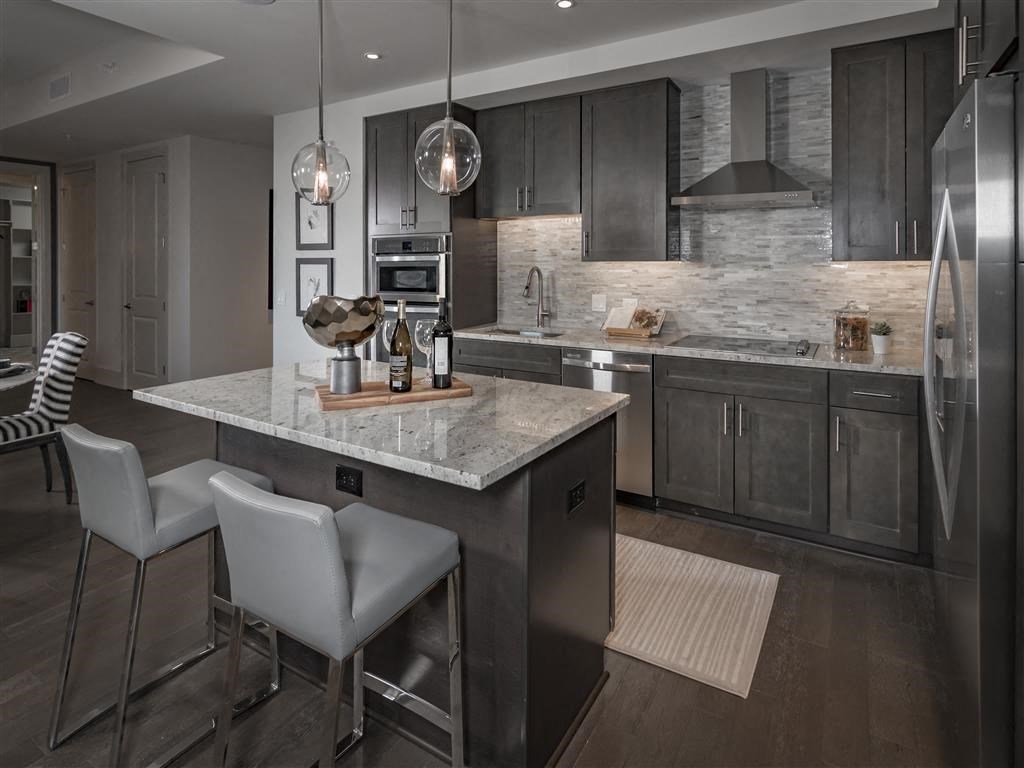 Large kitchen island with hardwood flooring and dark cabinets
