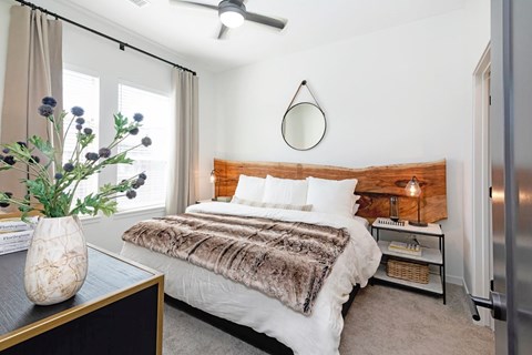 A bedroom with a bed, a vase with flowers, and a ceiling fan  at Bridges at Flatiron, Broomfield, 80021.