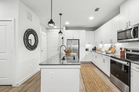 A modern kitchen with white cabinets and stainless steel appliances.