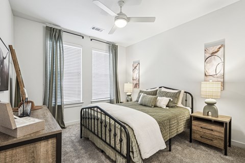 A bedroom with a bed, nightstand, and a painting on the wall.