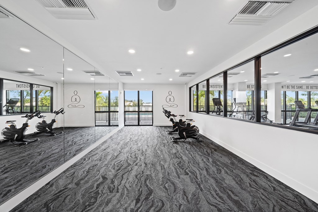 An indoor gym with exercise machines and large windows