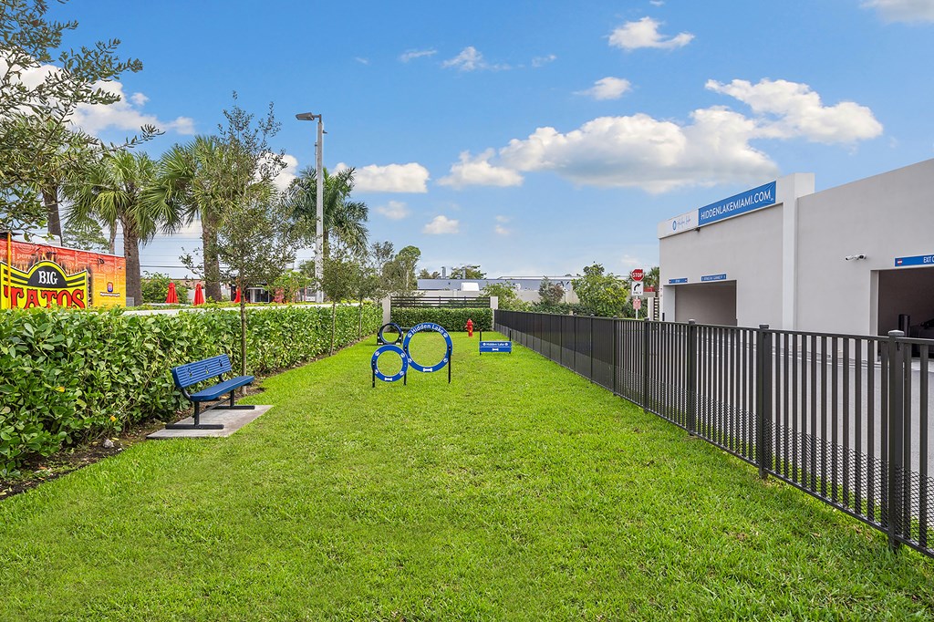 Fenced in dog park with grass and benches