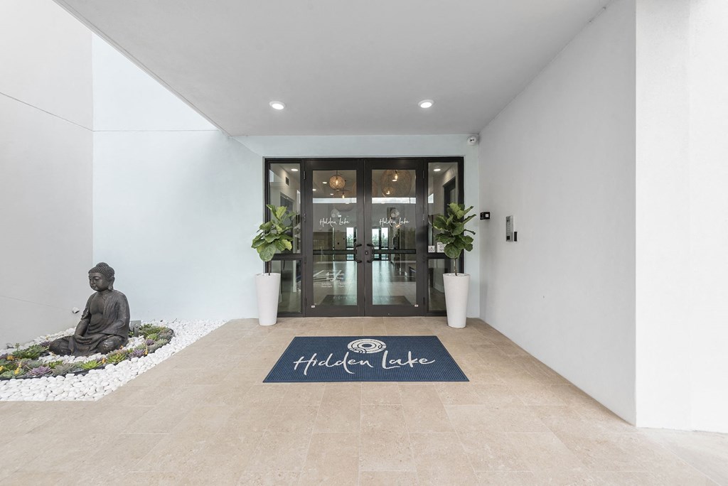 A statue of a buddha on the floor in front of a lobby door