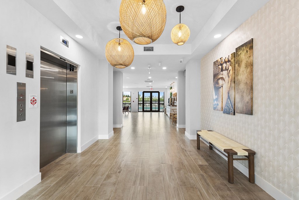 A long hallway with white walls and wood floors and large hanging lights