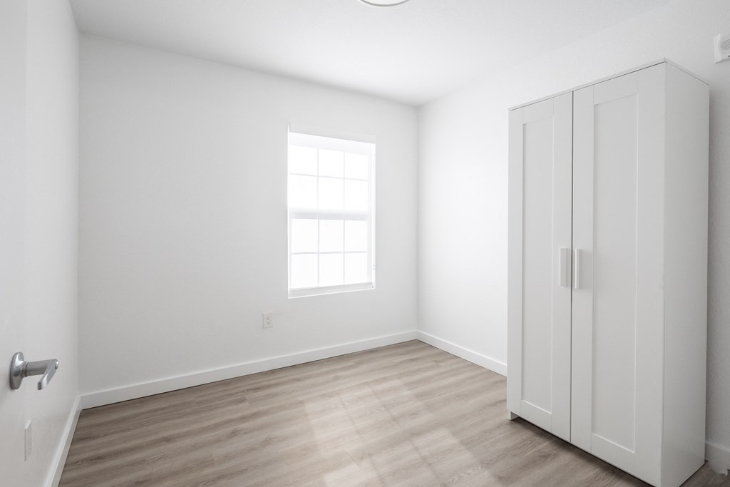 an empty room with white walls and a window and a closet