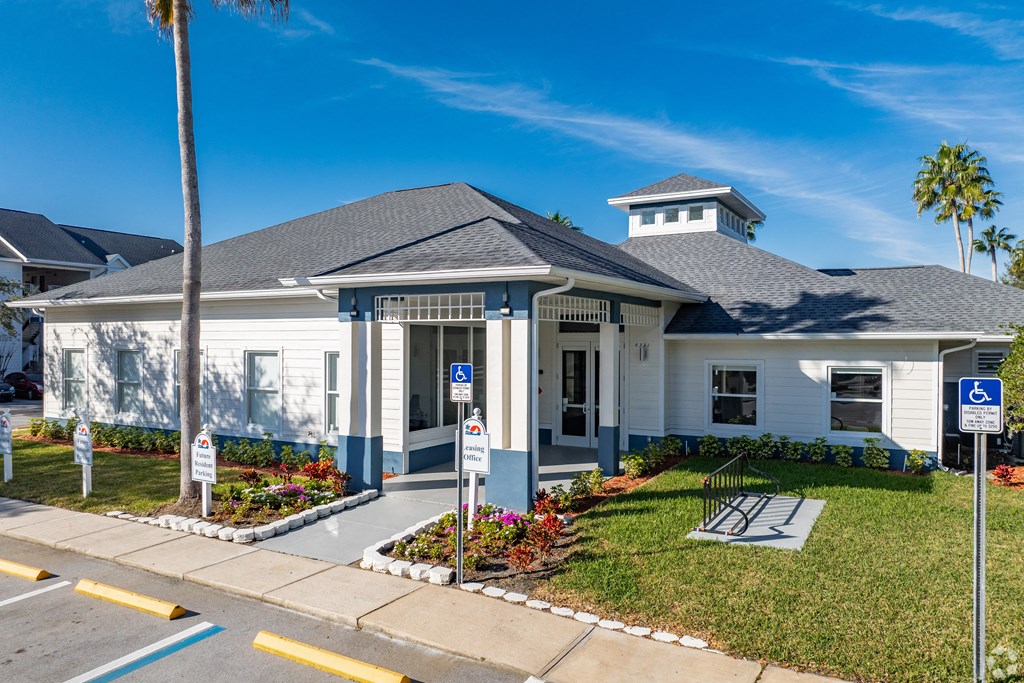 the front of a white house with palm trees and a parking lot