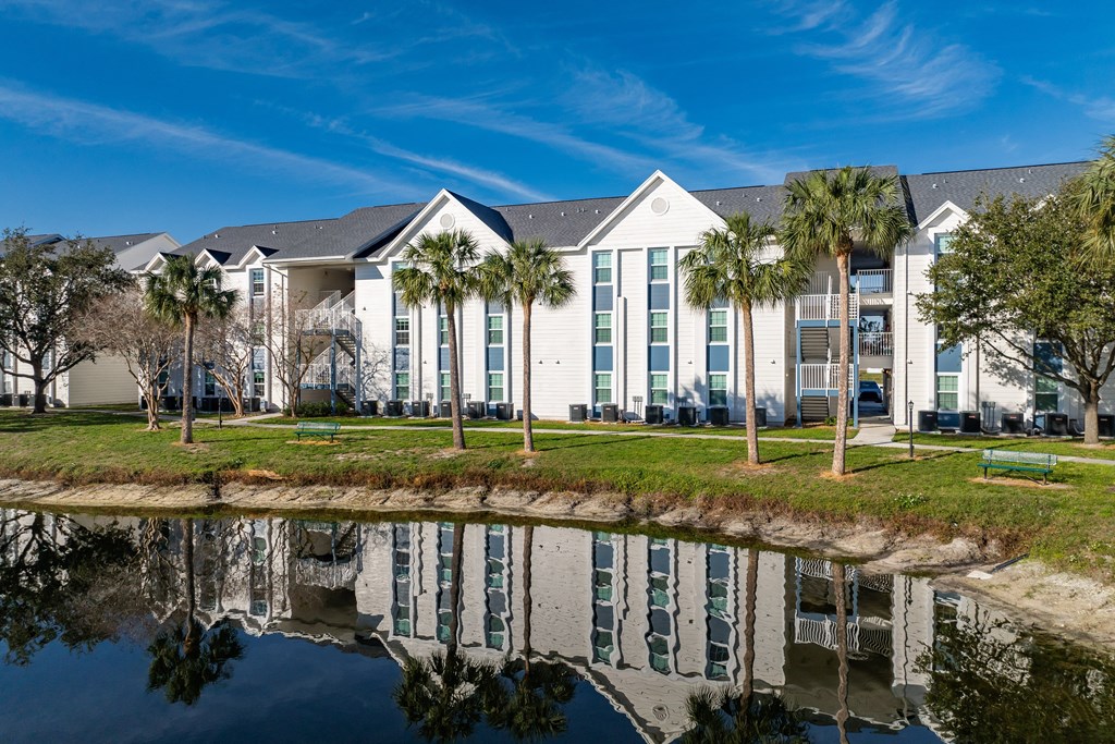 a building with palm trees in front of a body of water