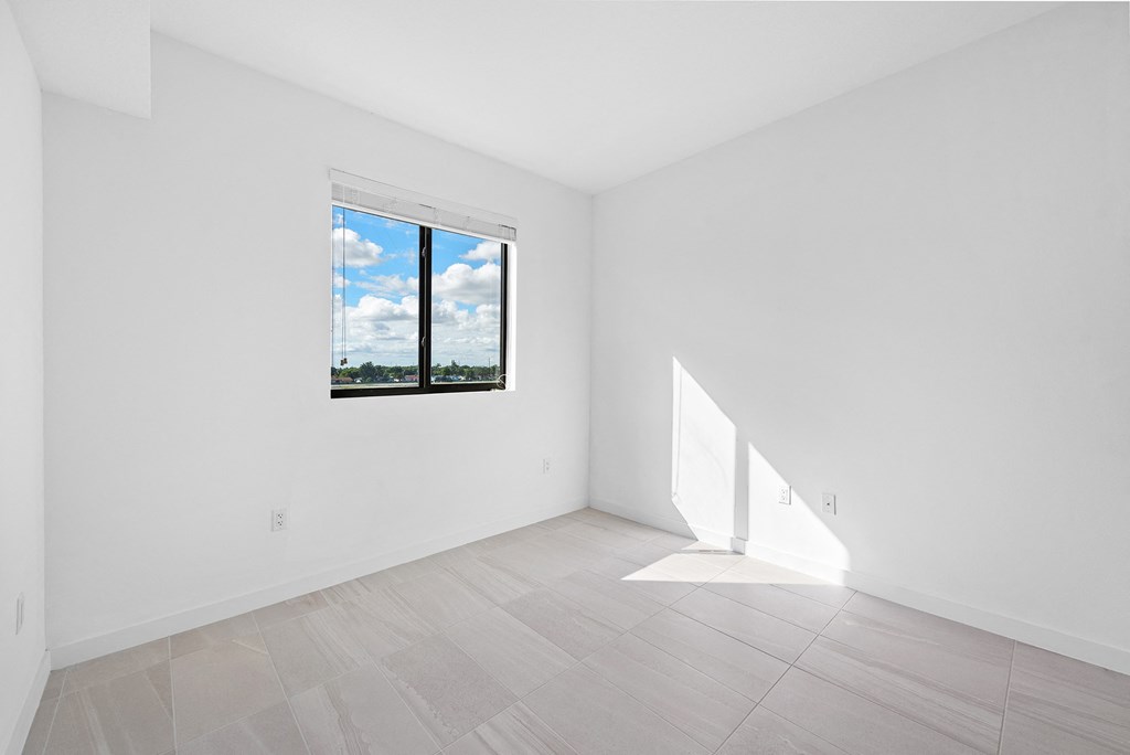 a bedroom with white walls and a window