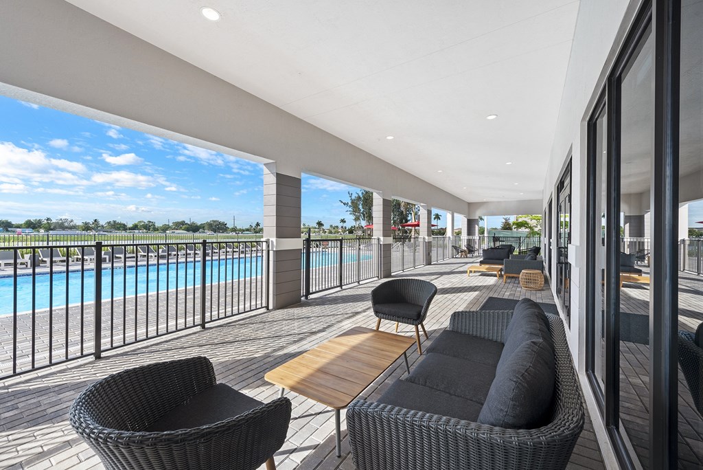 a large patio with chairs and tables and a pool in the background