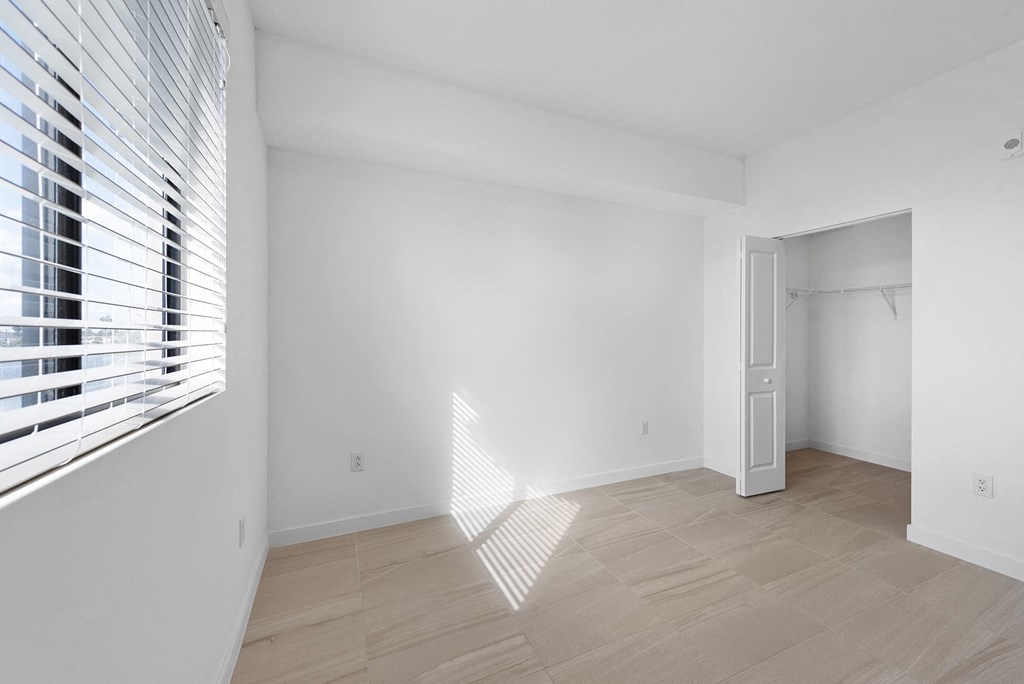 a bedroom with a large window and white walls
