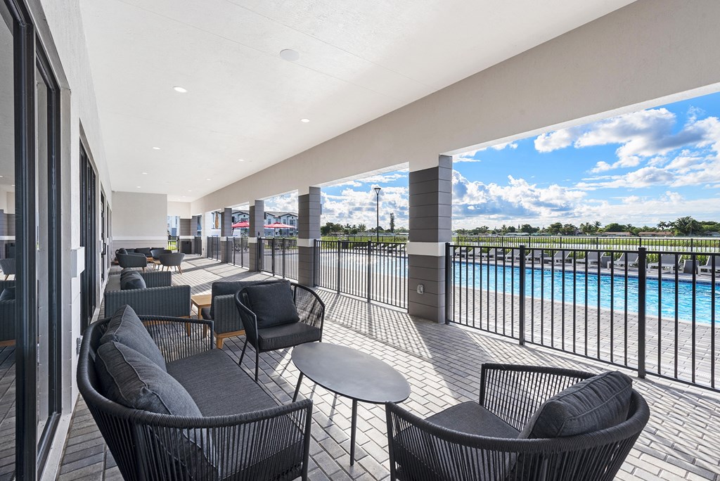 a patio with chairs and tables and a pool in the background