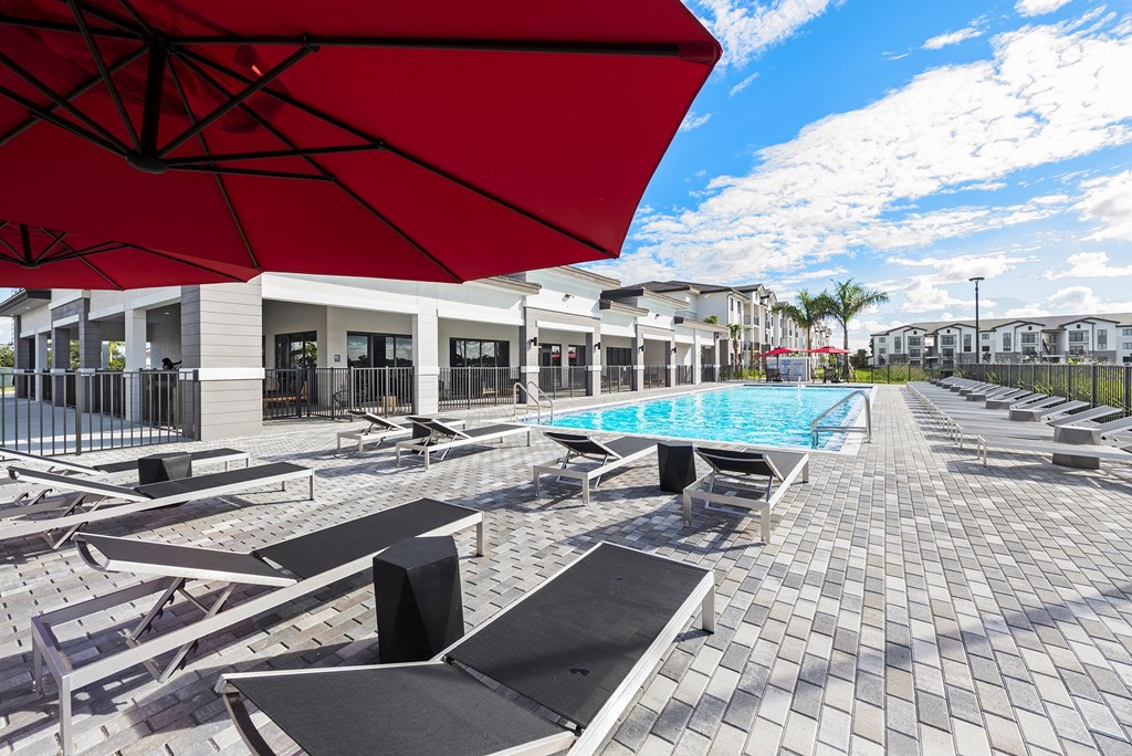 a pool with lounge chairs and umbrellas at the enclave at woodbridge apartments in sugar
