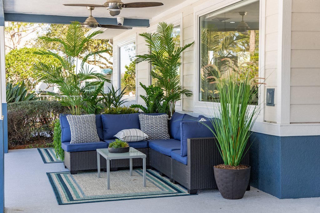 a porch with blue couches and potted plants