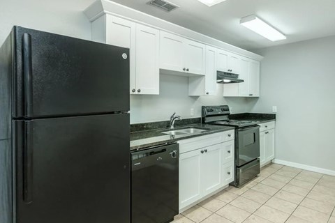a kitchen with a black refrigerator and white cabinets