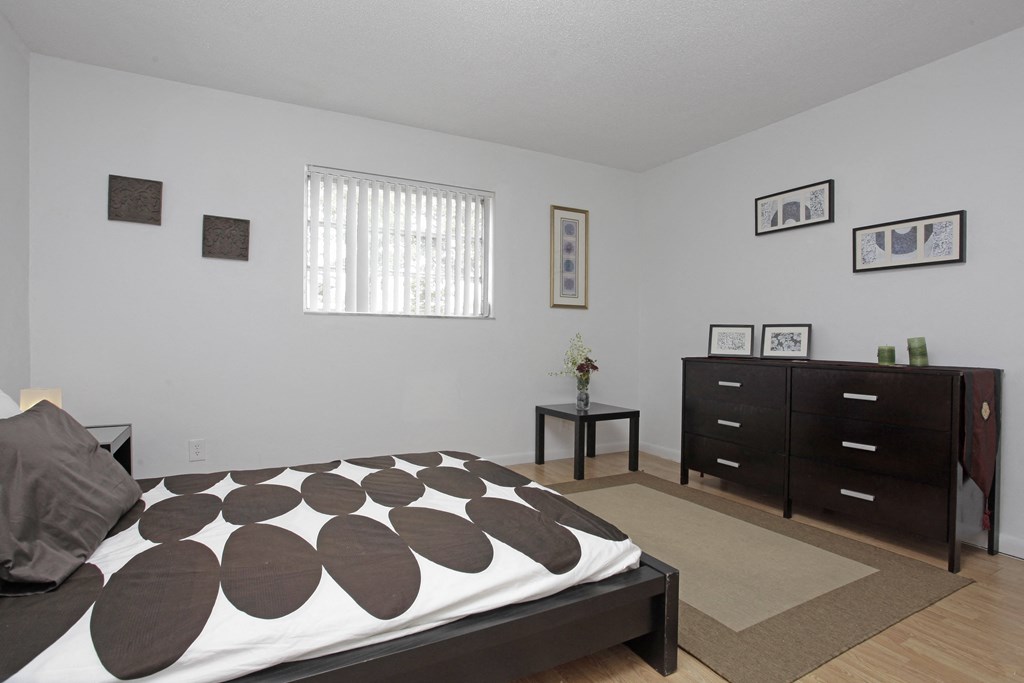 a bedroom with a bed with a black and white bedspread and a dresser