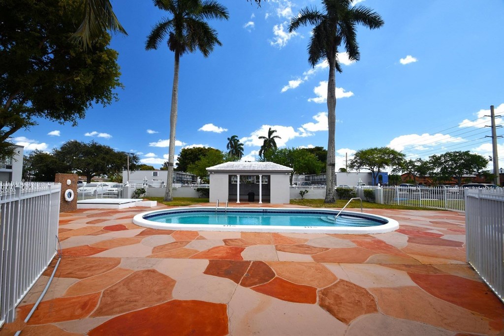 the pool is surrounded by palm trees and a white gazebo