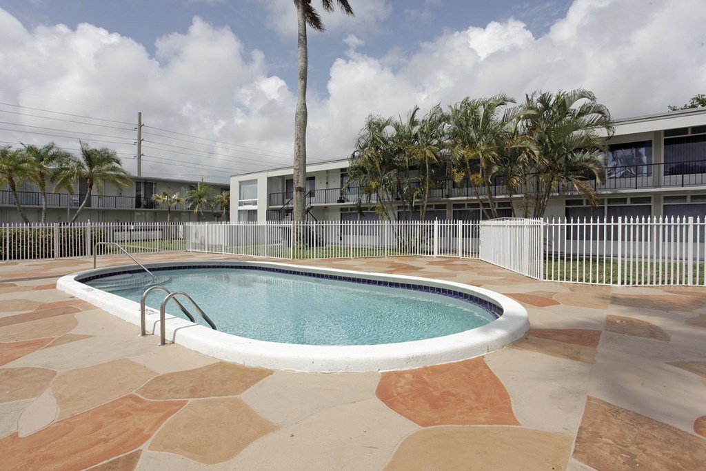 a swimming pool in front of a building with palm trees