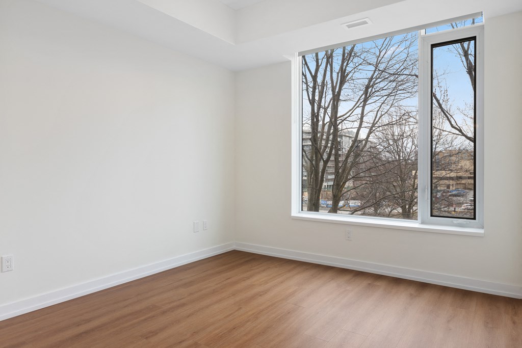 an empty room with wood floors and a large window