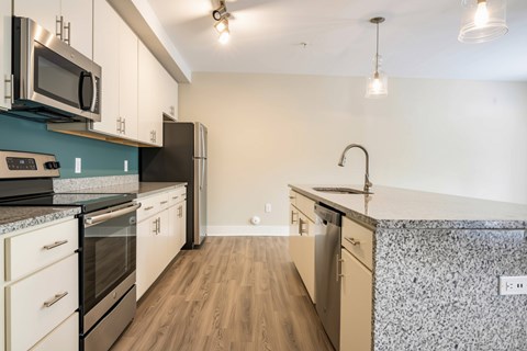 A kitchen with a black refrigerator and a black and white tiled backsplash.